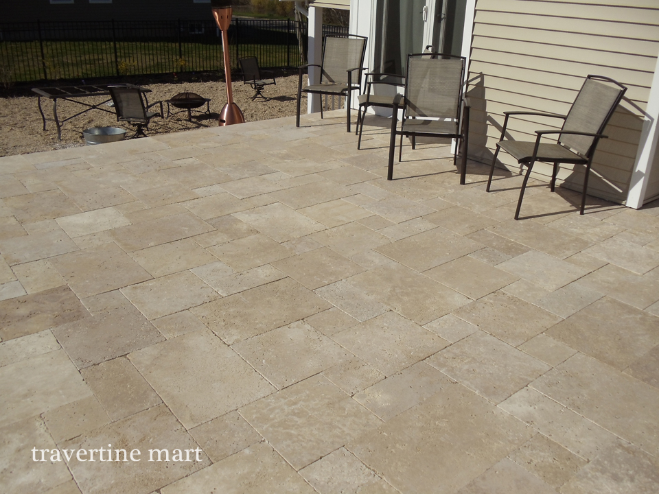 Walnut travertine paving in a real patio beside a home.