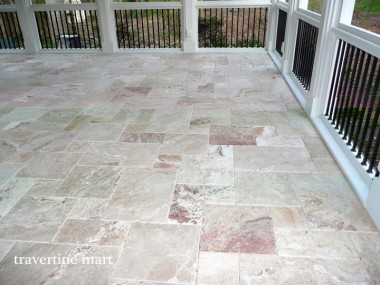 A light mixed-size tile floor meets the black railings and white framing of a screened porch.